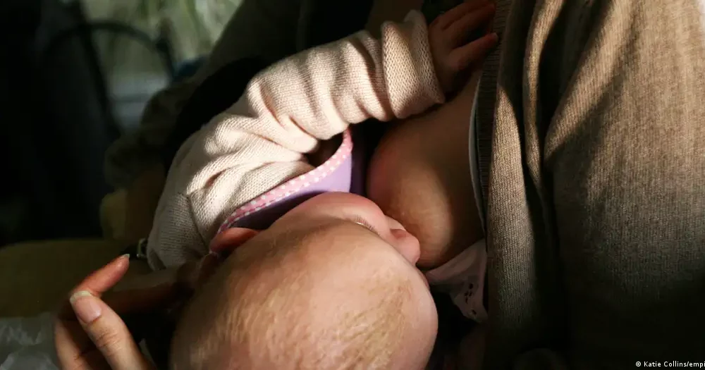 Baby lies on the breast and is breastfed.