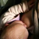 Baby lies on the breast and is breastfed.